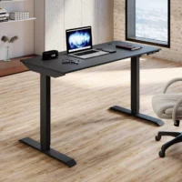 A sleek, modern adjustable height electric table with a minimalist design, showing the tabletop raised to a standing position in a home office setting