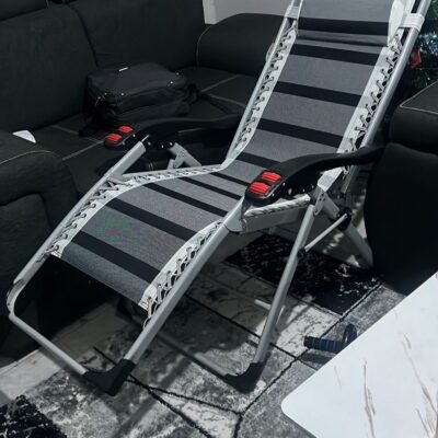 Foldable Full Recliner Lawn Chair in a reclining position on a grassy outdoor surface with adjustable armrests and cup holder.