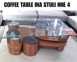 A padded coffee table set with upholstered top and four matching stools tucked underneath, providing a stylish and functional addition to any living room.